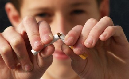 Close-up of man's fingers tearing apart a cigarette.